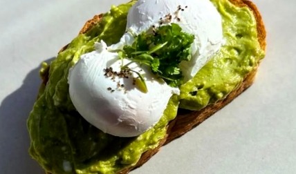 Avocado toast topped with poached eggs and fresh herbs